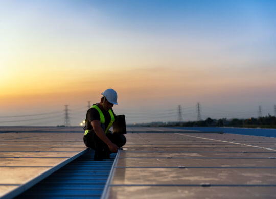 Technician checking Photovoltaic cells panels on factory roof